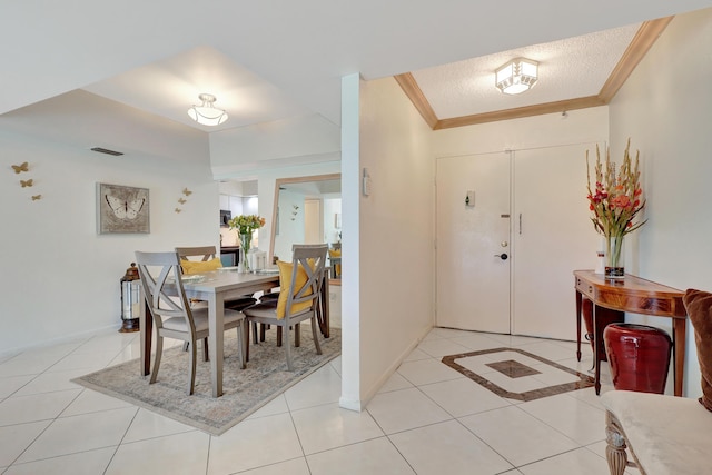 entrance foyer featuring light tile patterned floors, a textured ceiling, and ornamental molding