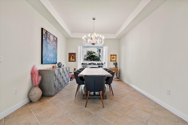 tiled dining area with an inviting chandelier and a tray ceiling