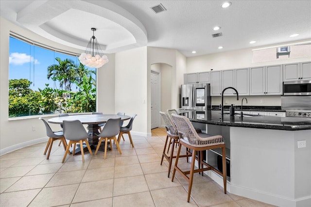 kitchen with gray cabinets, stainless steel appliances, pendant lighting, sink, and a raised ceiling