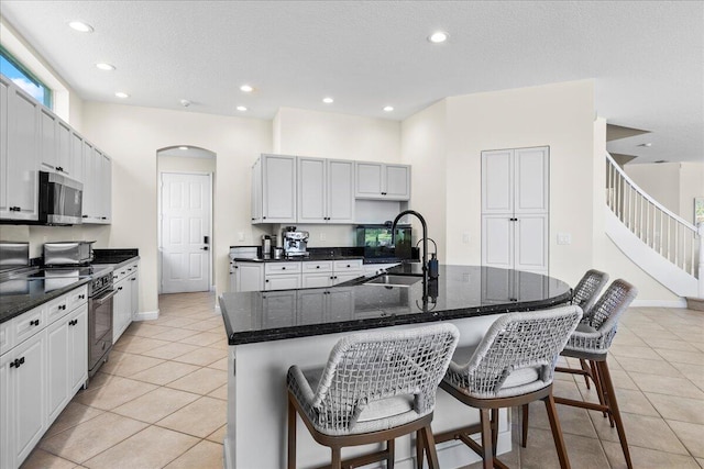 kitchen featuring appliances with stainless steel finishes, a breakfast bar area, a center island with sink, sink, and light tile patterned flooring