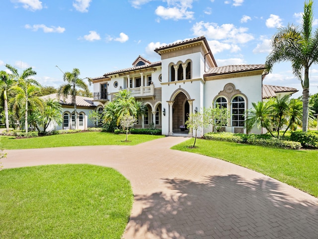 mediterranean / spanish-style house featuring a balcony and a front yard