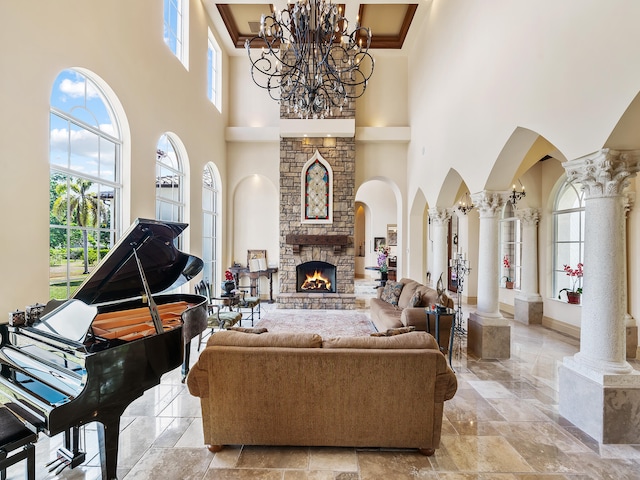 living room with a high ceiling, a fireplace, and ornate columns