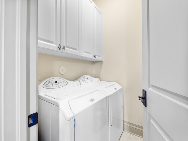 laundry room with light tile patterned floors, separate washer and dryer, and cabinets