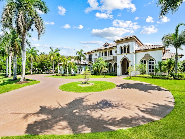 mediterranean / spanish home with a balcony and a front lawn