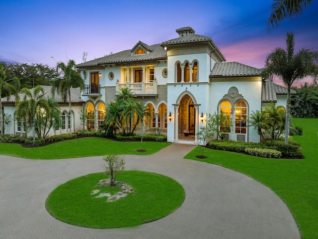 mediterranean / spanish-style house featuring a balcony and a yard