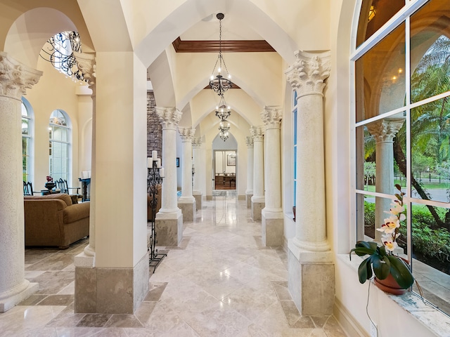 hall with ornate columns, a healthy amount of sunlight, tile patterned flooring, and a high ceiling