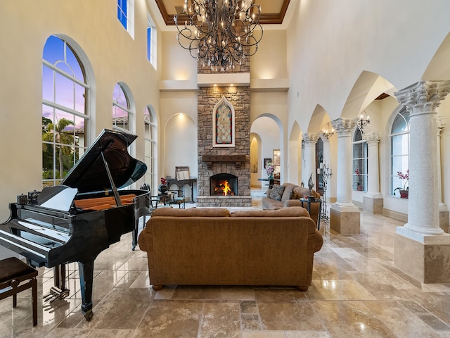 interior space with ornate columns, a stone fireplace, a towering ceiling, and a chandelier