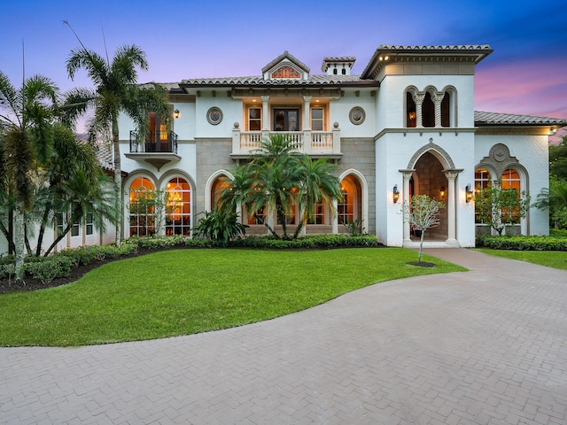 mediterranean / spanish-style house featuring a balcony and a lawn