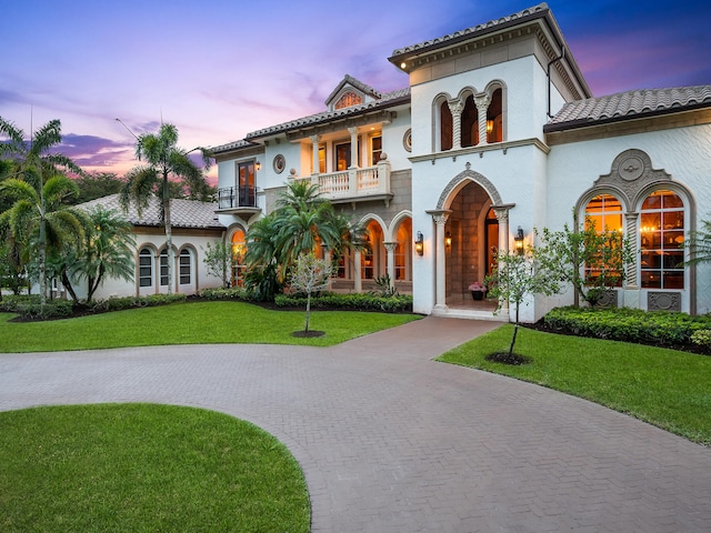 mediterranean / spanish home with a balcony and a lawn