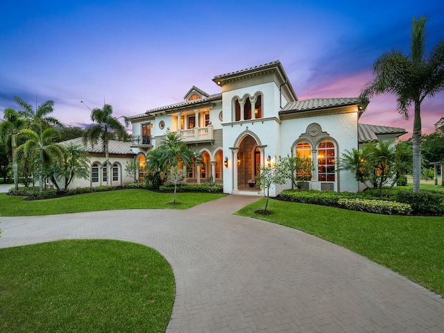 mediterranean / spanish home featuring a balcony and a yard