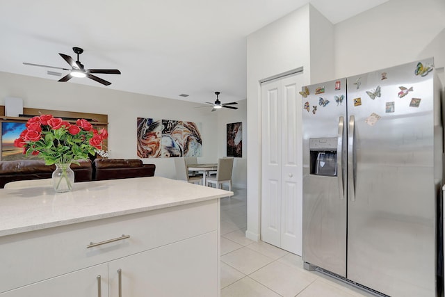 kitchen featuring light stone countertops, white cabinetry, light tile patterned flooring, ceiling fan, and stainless steel refrigerator with ice dispenser