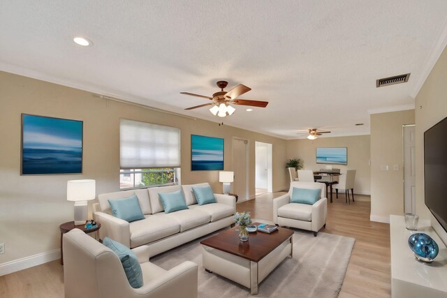 living room featuring a textured ceiling, light hardwood / wood-style flooring, ceiling fan, and ornamental molding