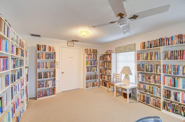 sitting room featuring a textured ceiling, carpet floors, and ceiling fan