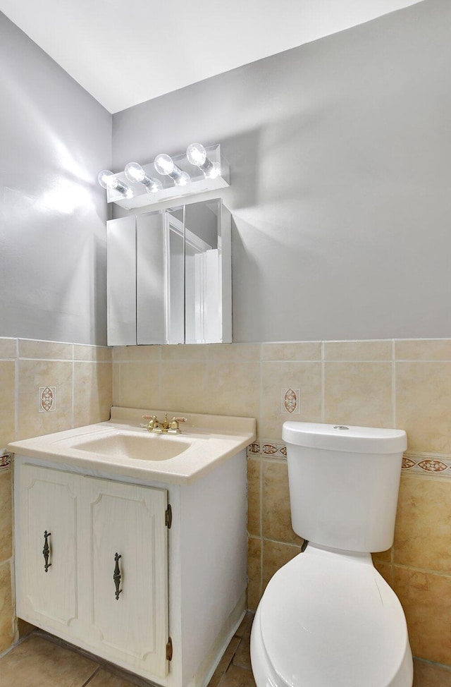 bathroom featuring toilet, tile patterned floors, and tile walls