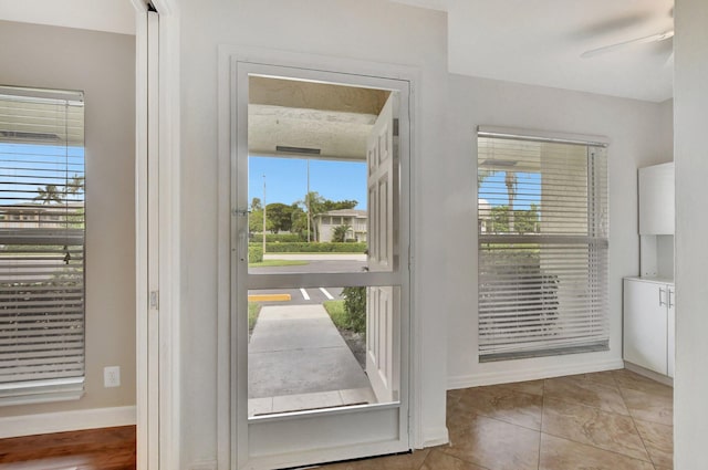 doorway featuring light tile patterned floors and ceiling fan