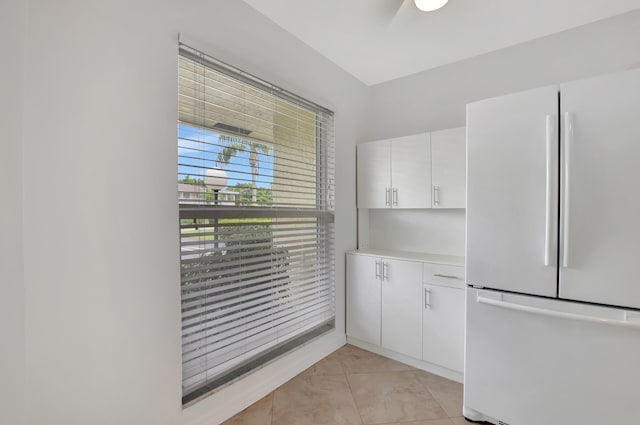 kitchen featuring light tile patterned floors, white refrigerator, and white cabinets