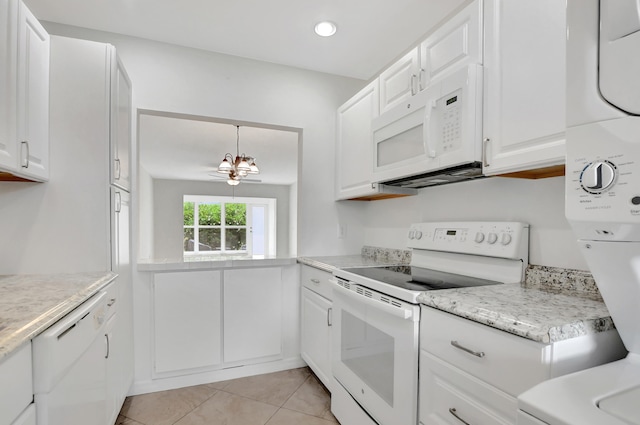 kitchen with stacked washer / drying machine, white appliances, light tile patterned floors, and white cabinets