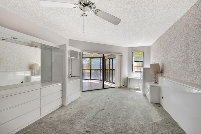 unfurnished bedroom featuring ceiling fan, light colored carpet, a textured ceiling, and access to outside