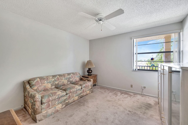 sitting room featuring light carpet, a textured ceiling, and ceiling fan