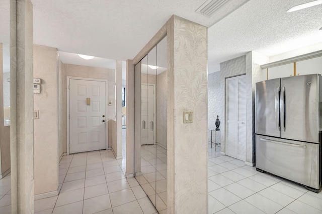 hallway with light tile patterned floors and a textured ceiling