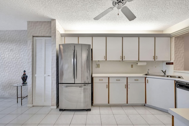 kitchen with white cabinets, a textured ceiling, stainless steel refrigerator, and sink