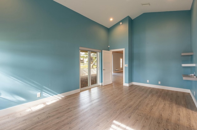 empty room featuring light wood-type flooring and high vaulted ceiling