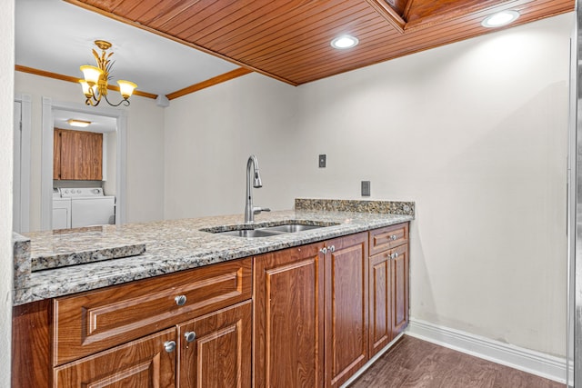 kitchen featuring washing machine and dryer, light stone counters, wood ceiling, and sink