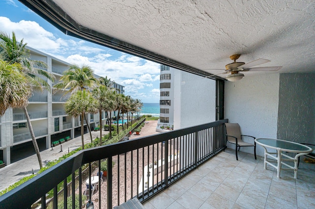 balcony featuring a water view and ceiling fan