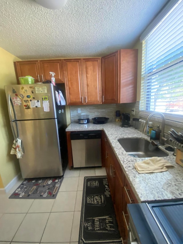 kitchen with backsplash, appliances with stainless steel finishes, sink, and light tile floors