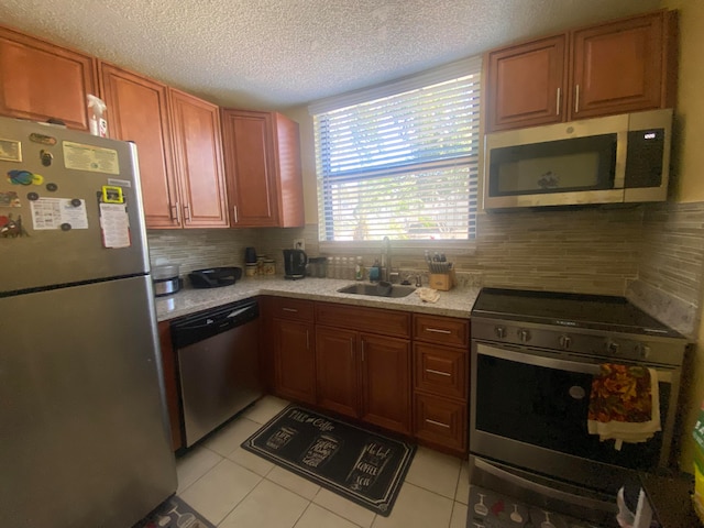 kitchen with appliances with stainless steel finishes, sink, backsplash, and light tile flooring