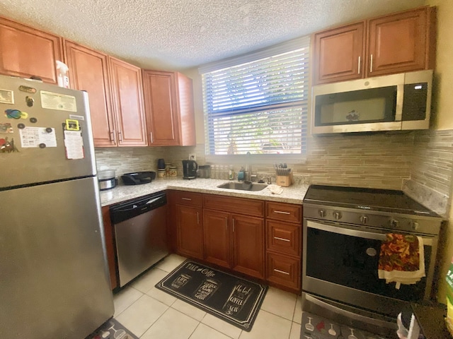 kitchen featuring appliances with stainless steel finishes, sink, backsplash, and light tile flooring