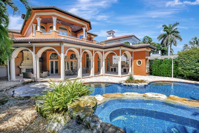 rear view of property with a swimming pool with hot tub, a patio area, and french doors