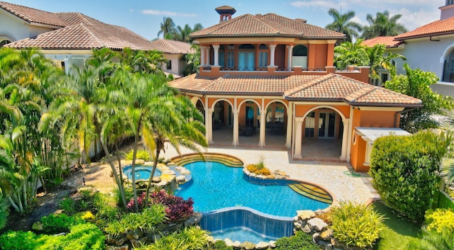 rear view of property with a patio area and a swimming pool with hot tub