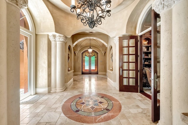 entryway with a notable chandelier, ornate columns, a high ceiling, and french doors