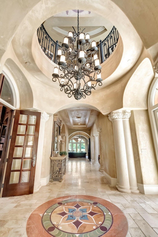 entryway featuring a high ceiling, an inviting chandelier, and ornate columns