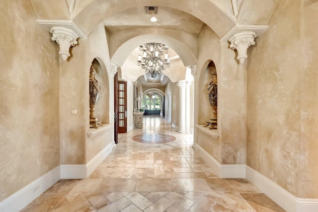 hallway featuring a chandelier and decorative columns