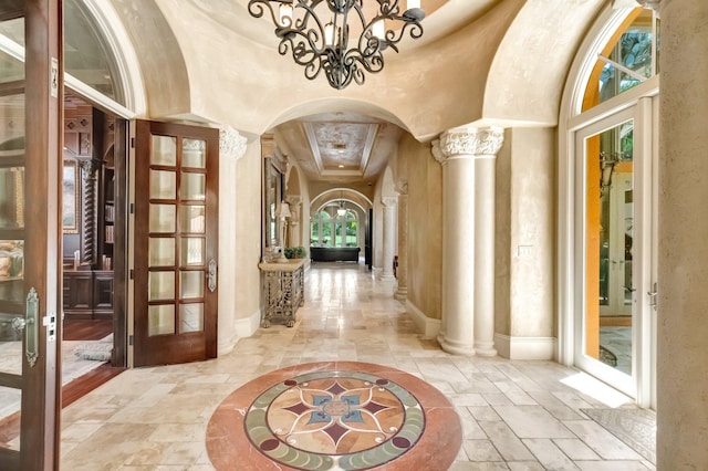 interior space featuring ornate columns, french doors, a high ceiling, and a notable chandelier