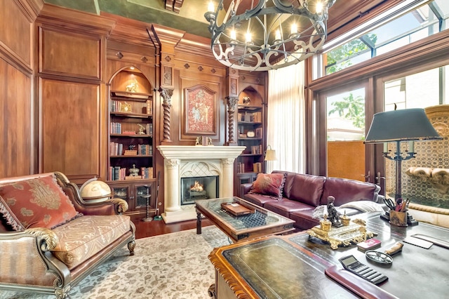 living room with built in shelves, wooden walls, a chandelier, and hardwood / wood-style flooring