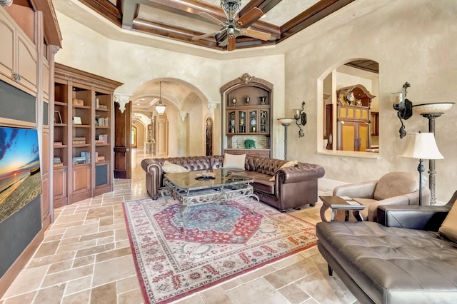 living room featuring beam ceiling, ceiling fan, a high ceiling, coffered ceiling, and ornamental molding