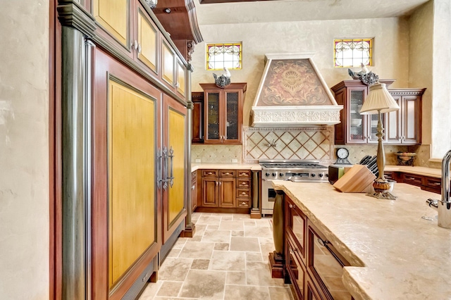 kitchen with decorative backsplash, stainless steel stove, and custom exhaust hood