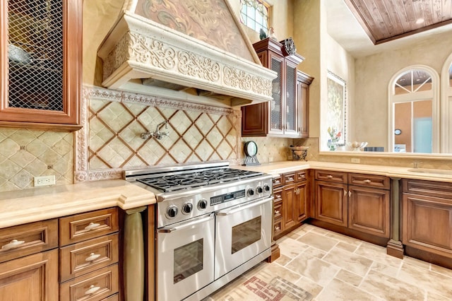 kitchen featuring decorative backsplash, custom range hood, and double oven range