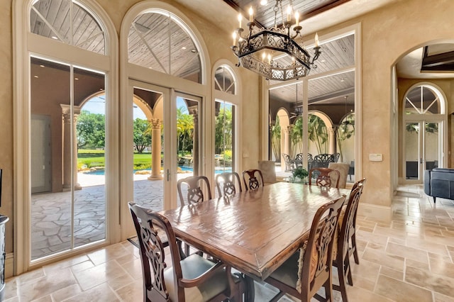 dining area featuring a chandelier, wood ceiling, a high ceiling, and french doors