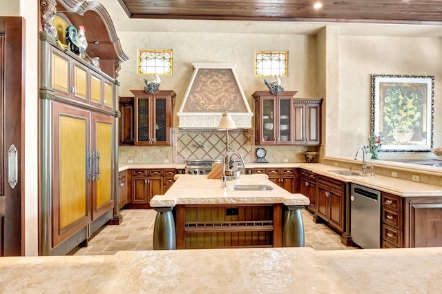 kitchen featuring a center island with sink, stainless steel dishwasher, custom range hood, and sink