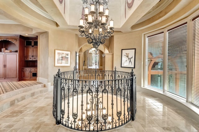 hallway with a chandelier, a high ceiling, and ornamental molding