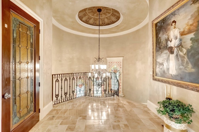 corridor with ornamental molding, a high ceiling, and an inviting chandelier