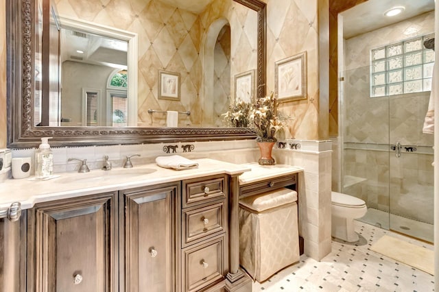 bathroom with a shower with door, vanity, tile walls, and toilet