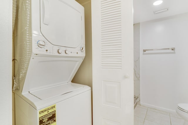 clothes washing area featuring light tile patterned floors and stacked washer and dryer