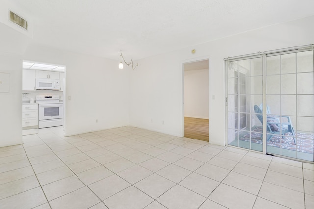 tiled spare room featuring a notable chandelier