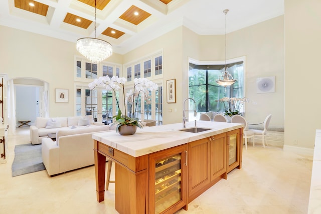 kitchen with pendant lighting, a high ceiling, coffered ceiling, and sink