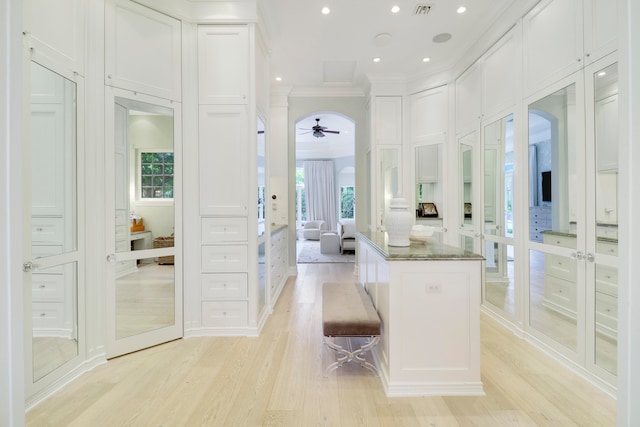 kitchen featuring crown molding, dark stone countertops, light hardwood / wood-style floors, a kitchen bar, and white cabinetry